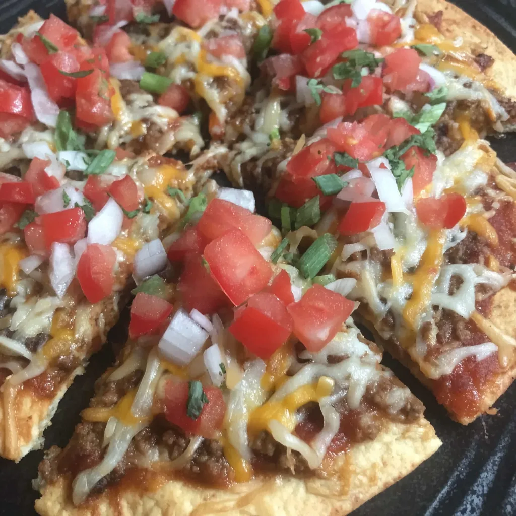 A slice of Mexican pizza with tomatoes and cheese.