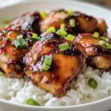 A bowl of rice with chicken and vegetables.