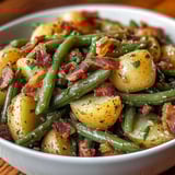 A bowl of food with green beans and bacon.