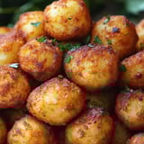 A pile of fried potatoes with green herbs on top.