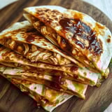 A stack of chicken tacos on a wooden table.