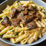A bowl of pasta with meat and vegetables.
