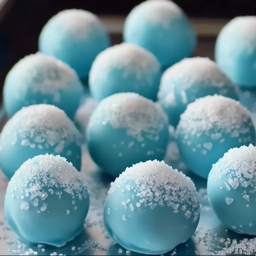 An assortment of blue truffles covered in sparkly white sugar crystals on a tray.