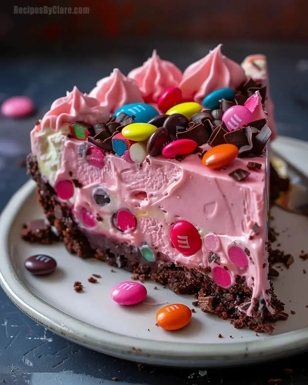 A slice of pink paradise no-bake cheesecake with M&M's and Snickers.