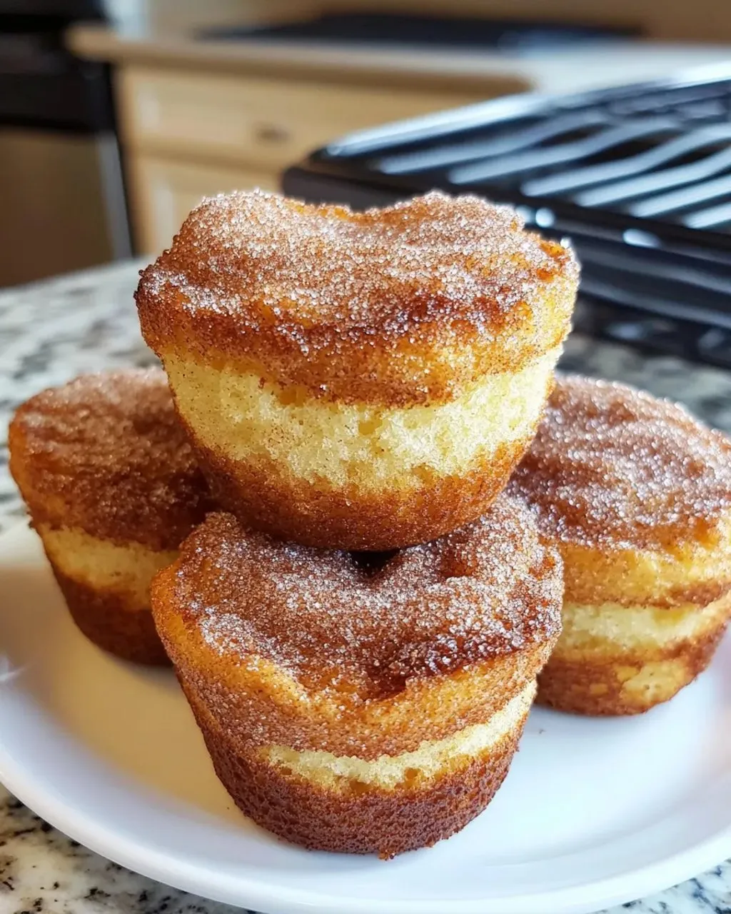 A stack of three cupcakes with sugar on top.