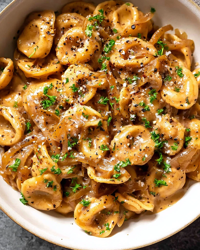 A bowl of pasta with French onions.