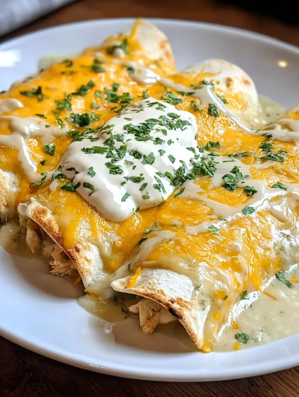 A plate of chicken enchiladas with white sauce on top.
