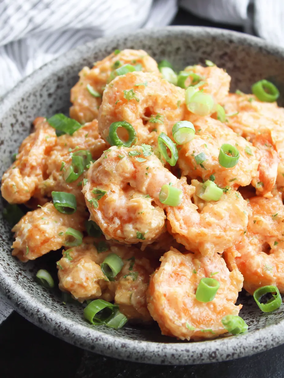 A bowl of shrimp with green onions and spices.
