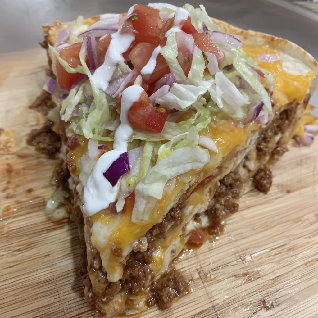 A slice of a casserole with lettuce, tomatoes, and cheese.