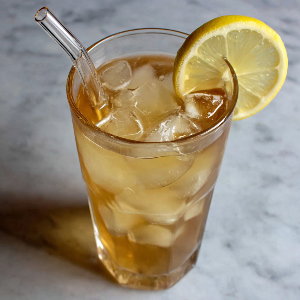 A glass of homemade ginger ale with a lemon wedge on top.