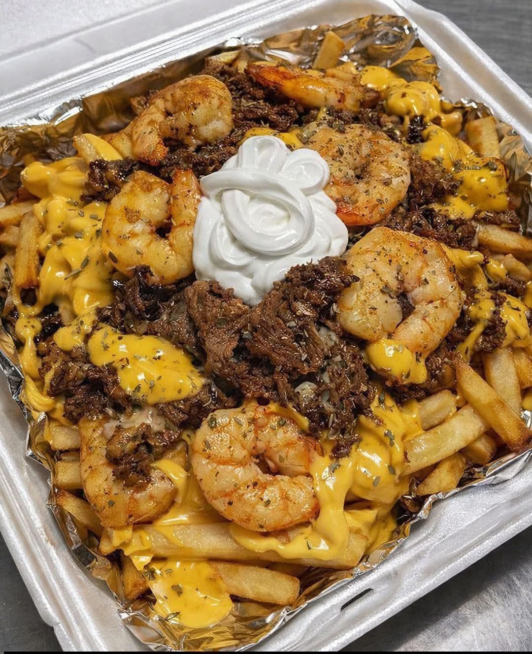 A plate of shrimp and cheese covered fries.