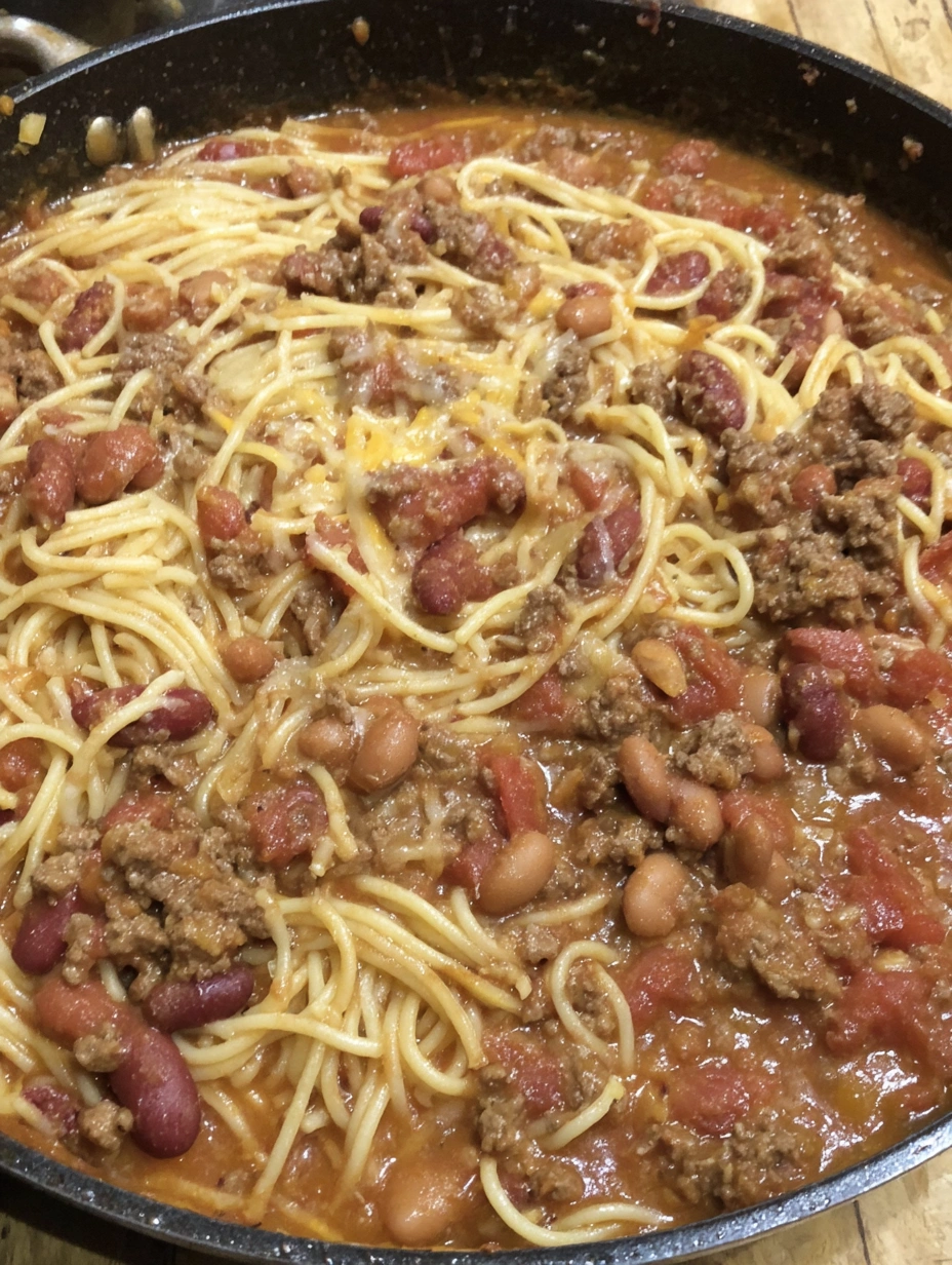 A bowl of spaghetti with meat and beans.