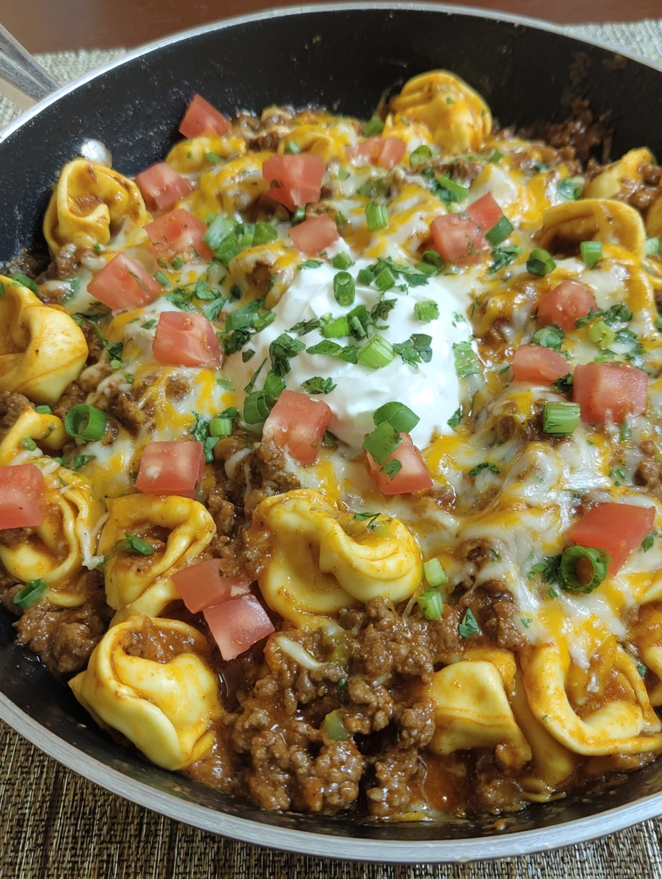 A skillet filled with cheesy taco tortellini.