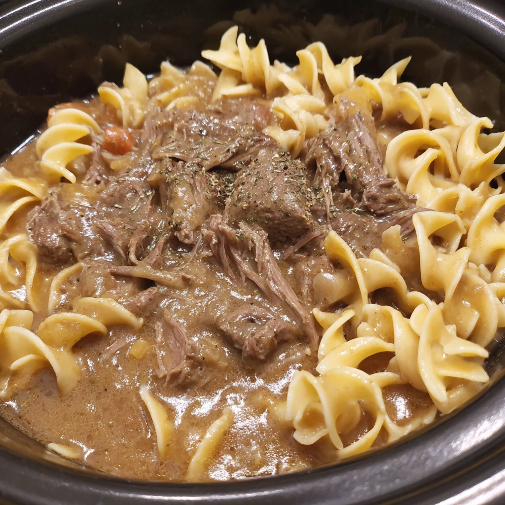 A bowl of beef and noodles in the crockpot.