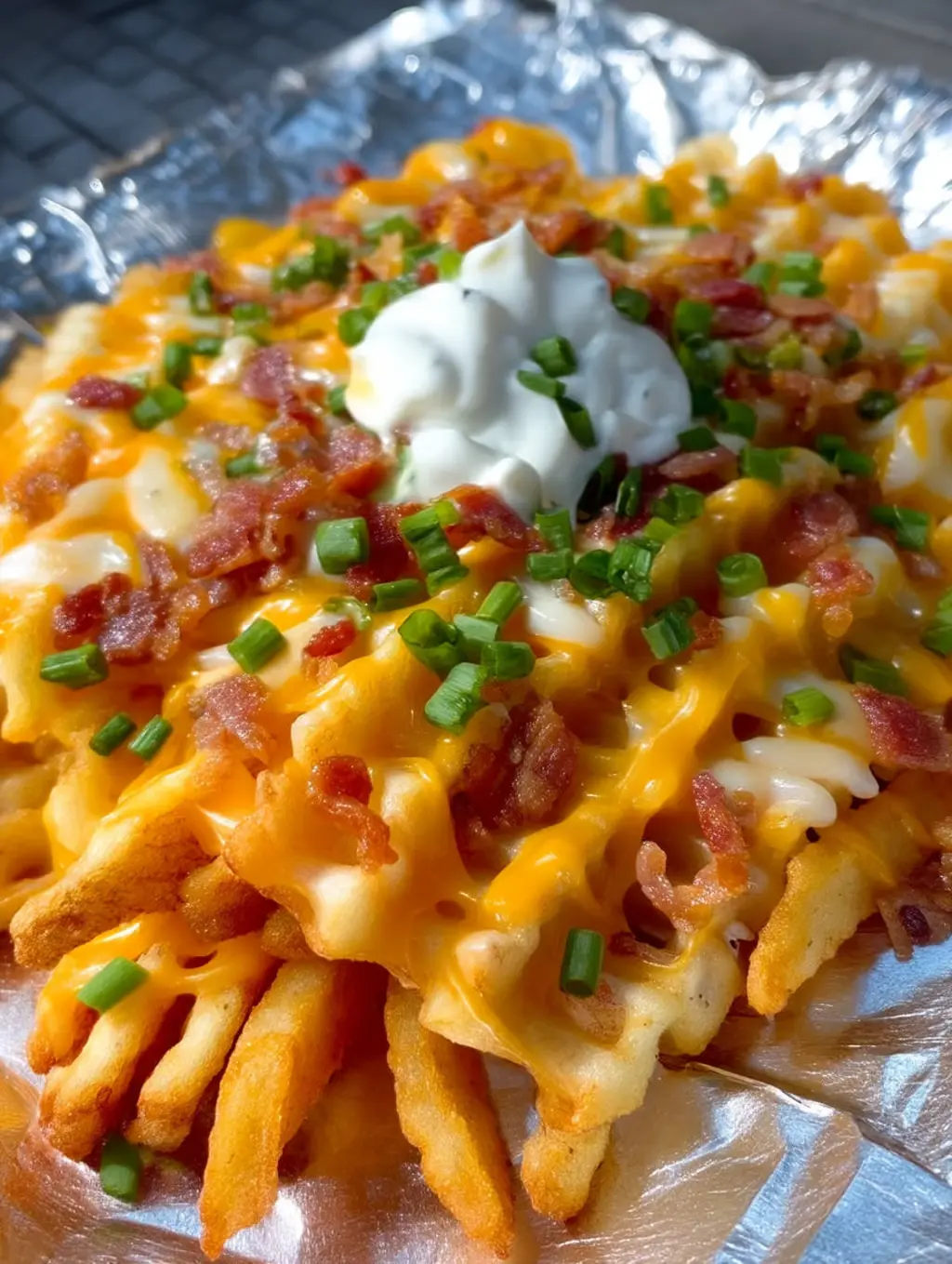 A close up of a bacon and cheese loaded fries.
