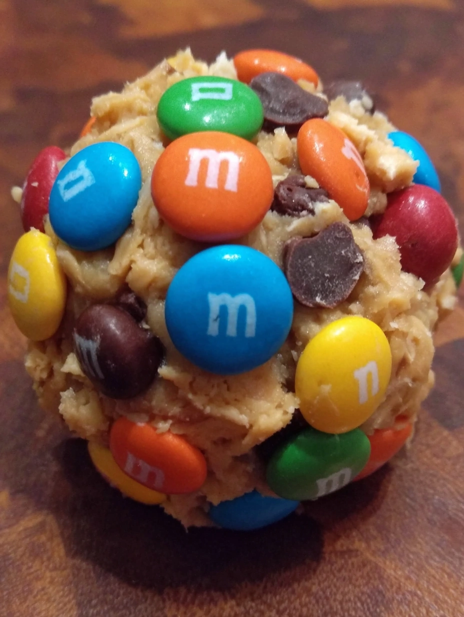 A large ball of cookie dough with M&amp;M's on top.