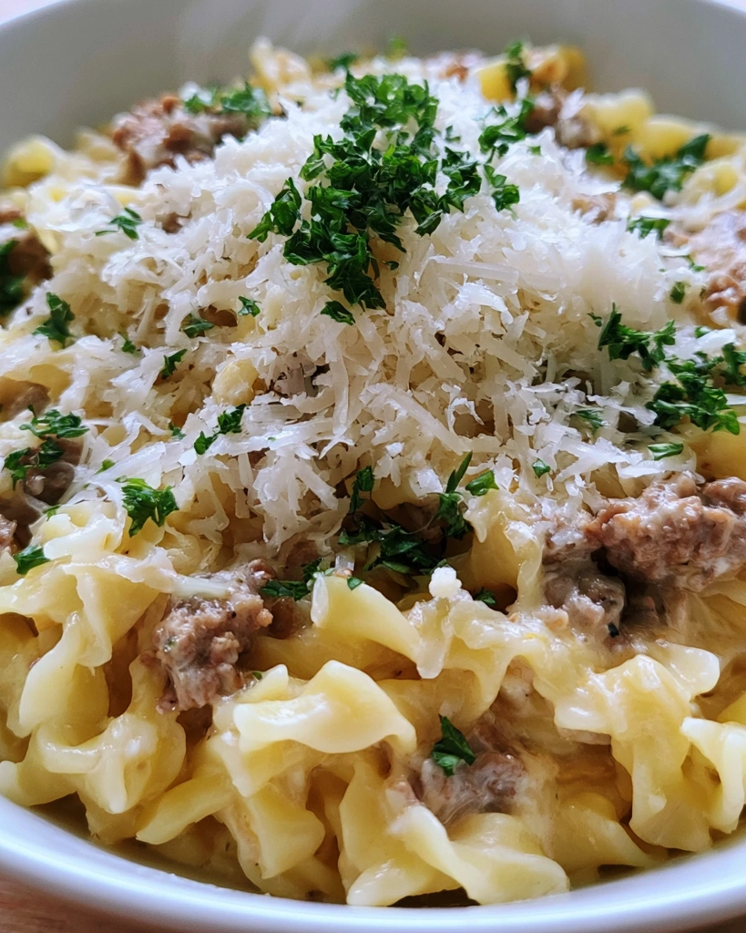 A bowl of pasta with cheese and meat.