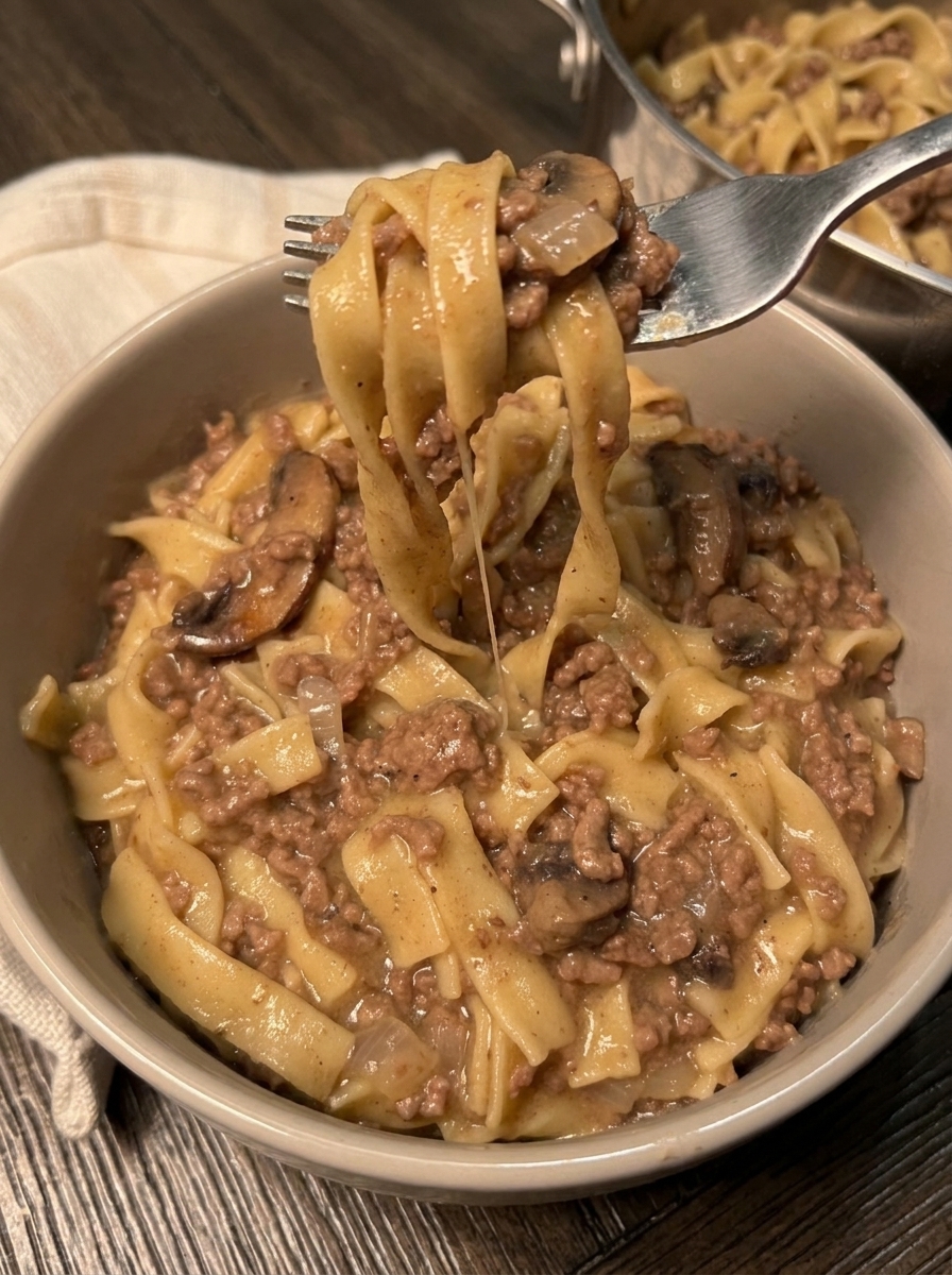 A bowl of beef stroganoff with noodles and mushrooms.