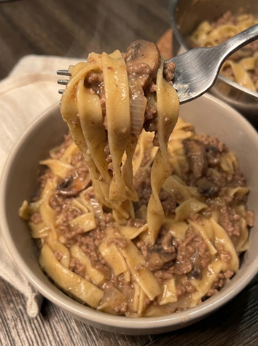 A fork is in a bowl of beef stroganoff.