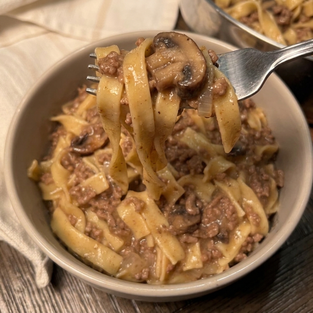 A bowl of beef stroganoff with a fork in it.