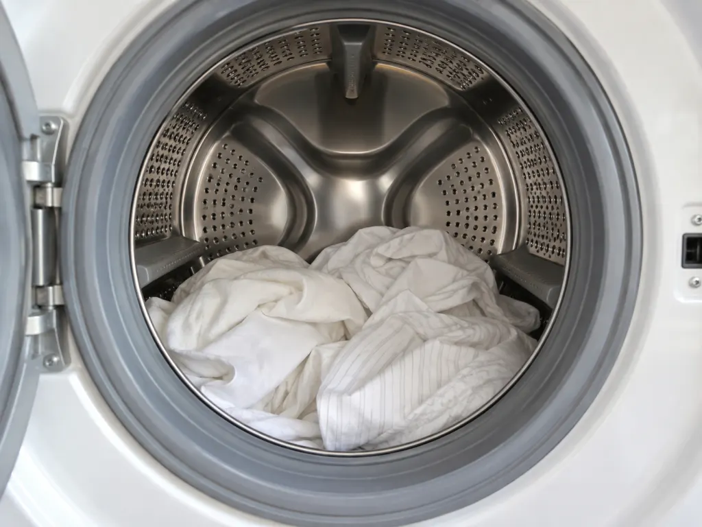 A washer drum loaded with loose sheets and enough open space for movement.