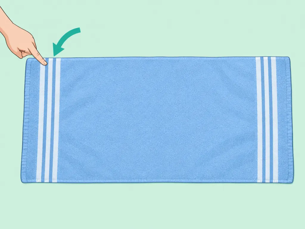 A hand points to stripes near the end of a bath towel.
