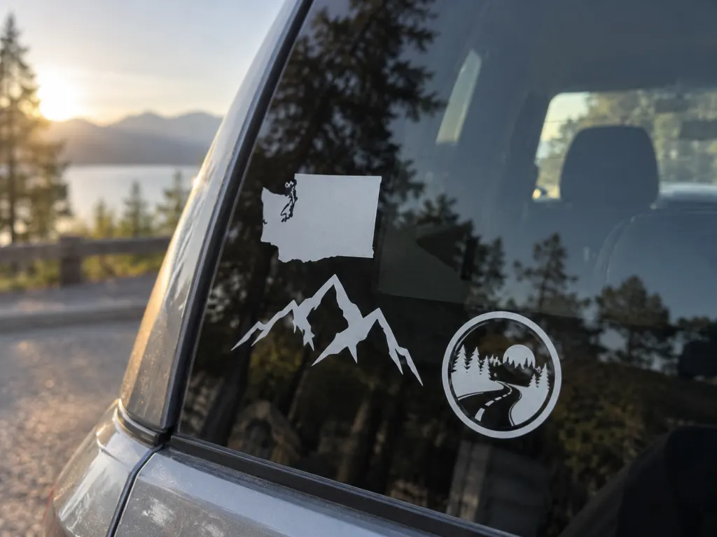 Close-up of personal travel-style decals on a car window, including a rotated state outline.