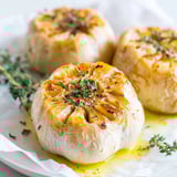Three garlic cloves roasted in a pan.