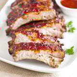 A plate of ribs with sauce on it.