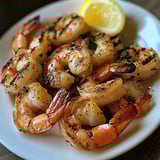 A plate of grilled shrimp with garlic and lemon.